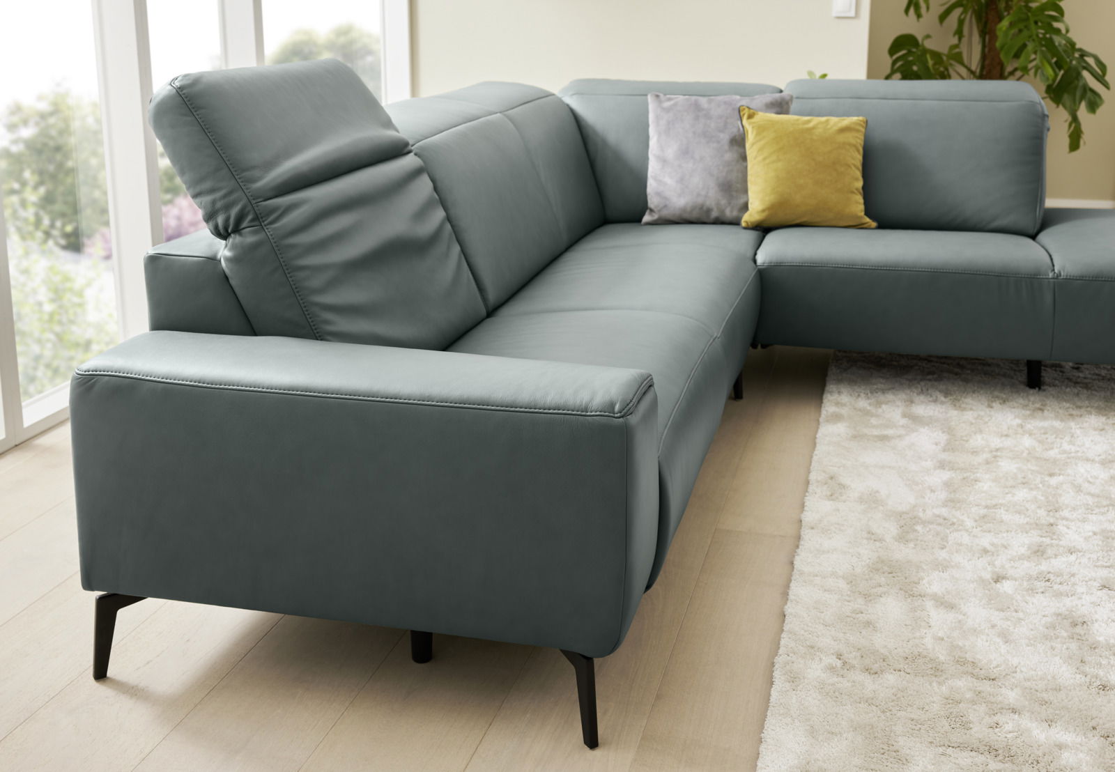 Ecksofa Musterring MR 1320 in einer modernen Wohnzimmerumgebung, seitliche Perspektive mit grauem Bezug und bunten Kissen.