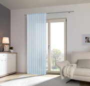 Heller, transparenter Fertigvorhang in einem modernen Wohnzimmer, aufgehängt vor einer großen Fensterfront mit Blick ins Freie.