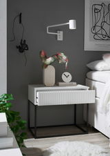 Moderne Nachtkommode mit geriffelter Front in einem stilvollen Schlafzimmer, seitliche Perspektive.