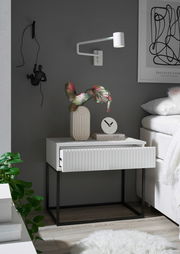 Moderne Nachtkommode mit geriffelter Front in einem stilvollen Schlafzimmer, seitliche Perspektive.