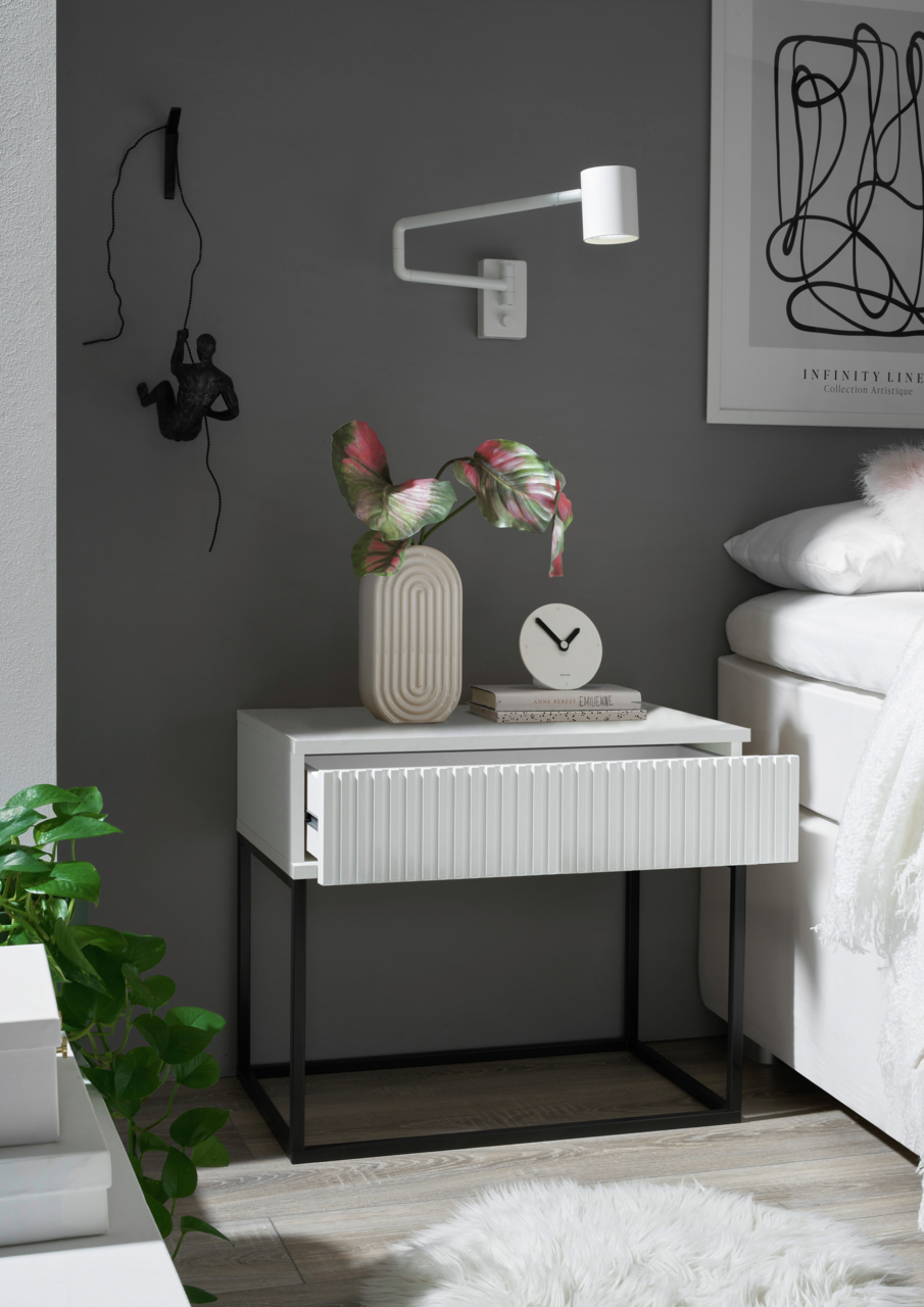 Moderne Nachtkommode mit geriffelter Front in einem stilvollen Schlafzimmer, seitliche Perspektive.