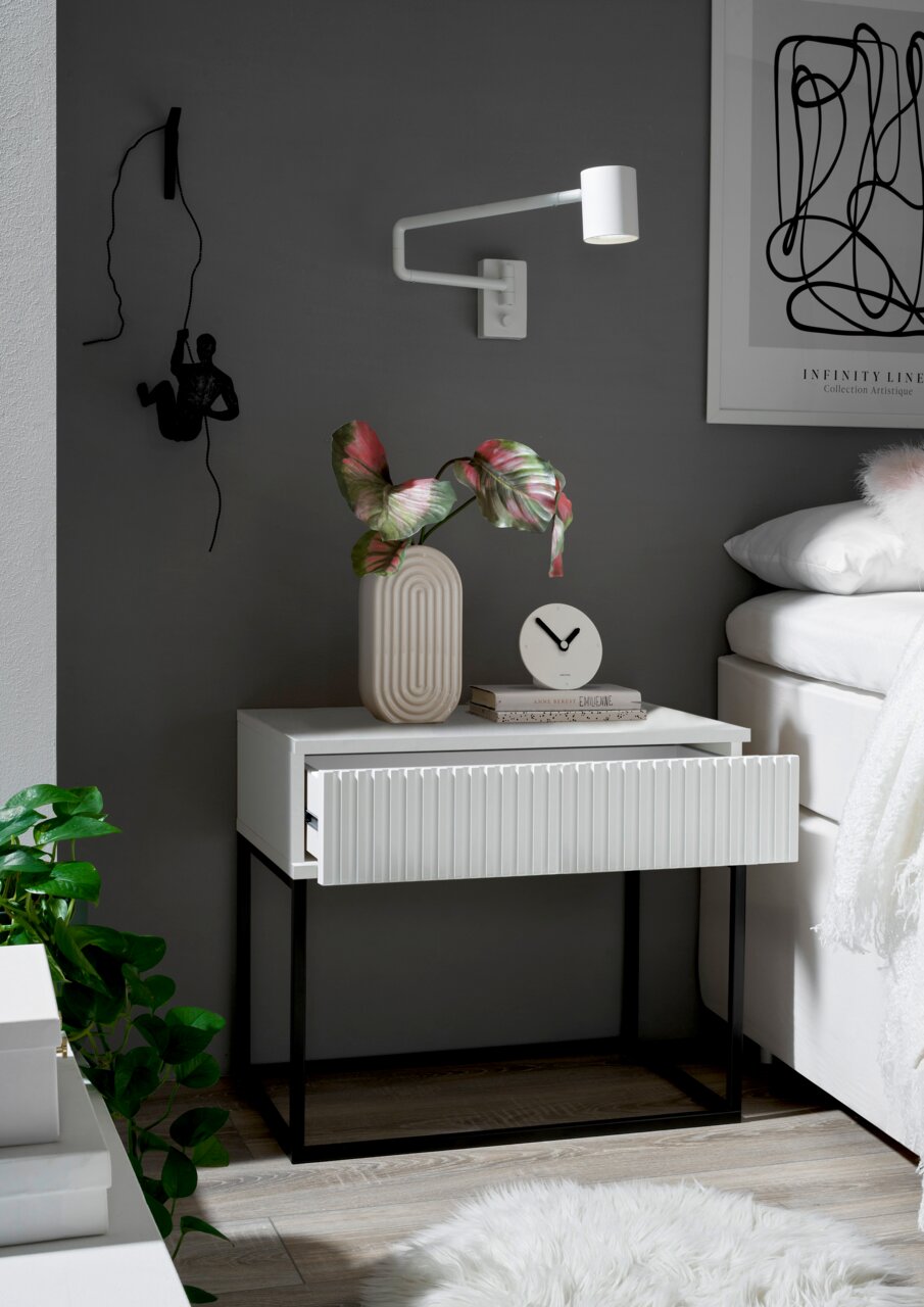 Moderne Nachtkommode mit geriffelter Front in einem stilvollen Schlafzimmer, seitliche Perspektive.