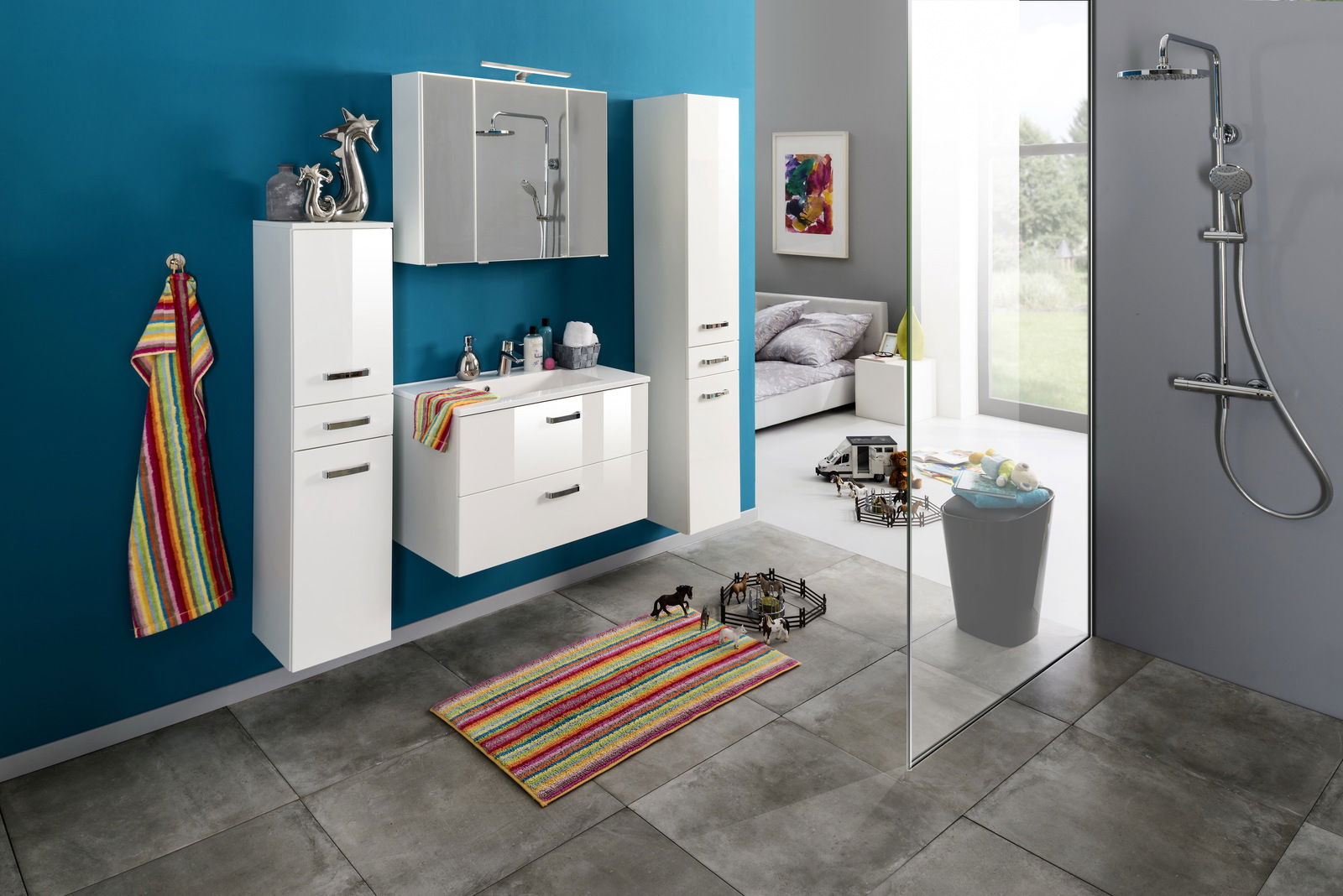 Moderner Badezimmerbereich mit Spiegelschrank, weißem Waschtisch und Hängeschränken, bunte Akzente durch Handtuch und Teppich, seitliche Perspektive