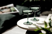 Zwei grüne Sekt- oder Dessertschalen auf einem runden Tisch, seitliche Perspektive.