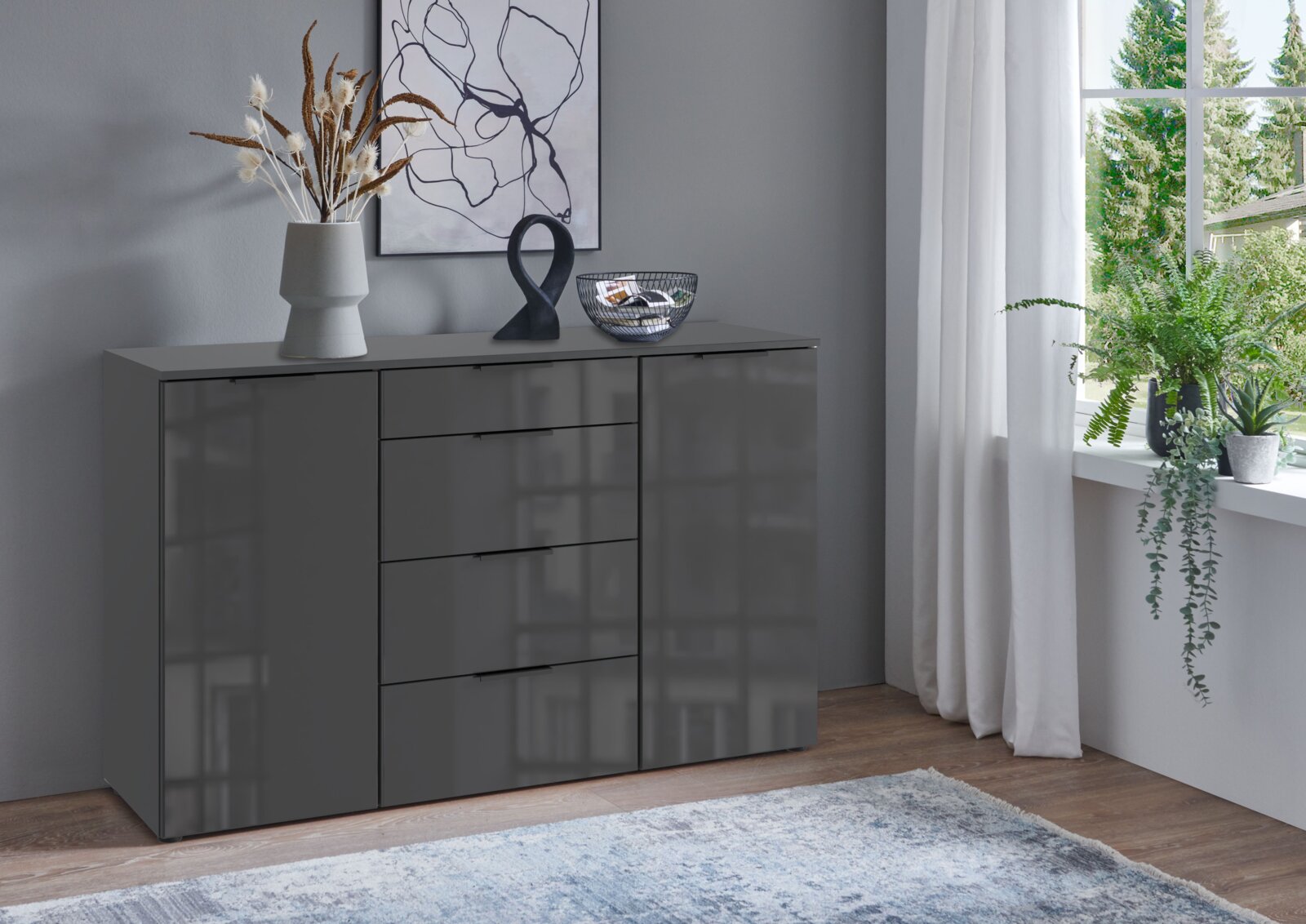 Moderne graue Kombikommode mit Schubladen und Türen, dekoriert mit einer Vase und Kunstobjekten, in einem stilvoll eingerichteten Raum mit Blick aus dem Fenster.