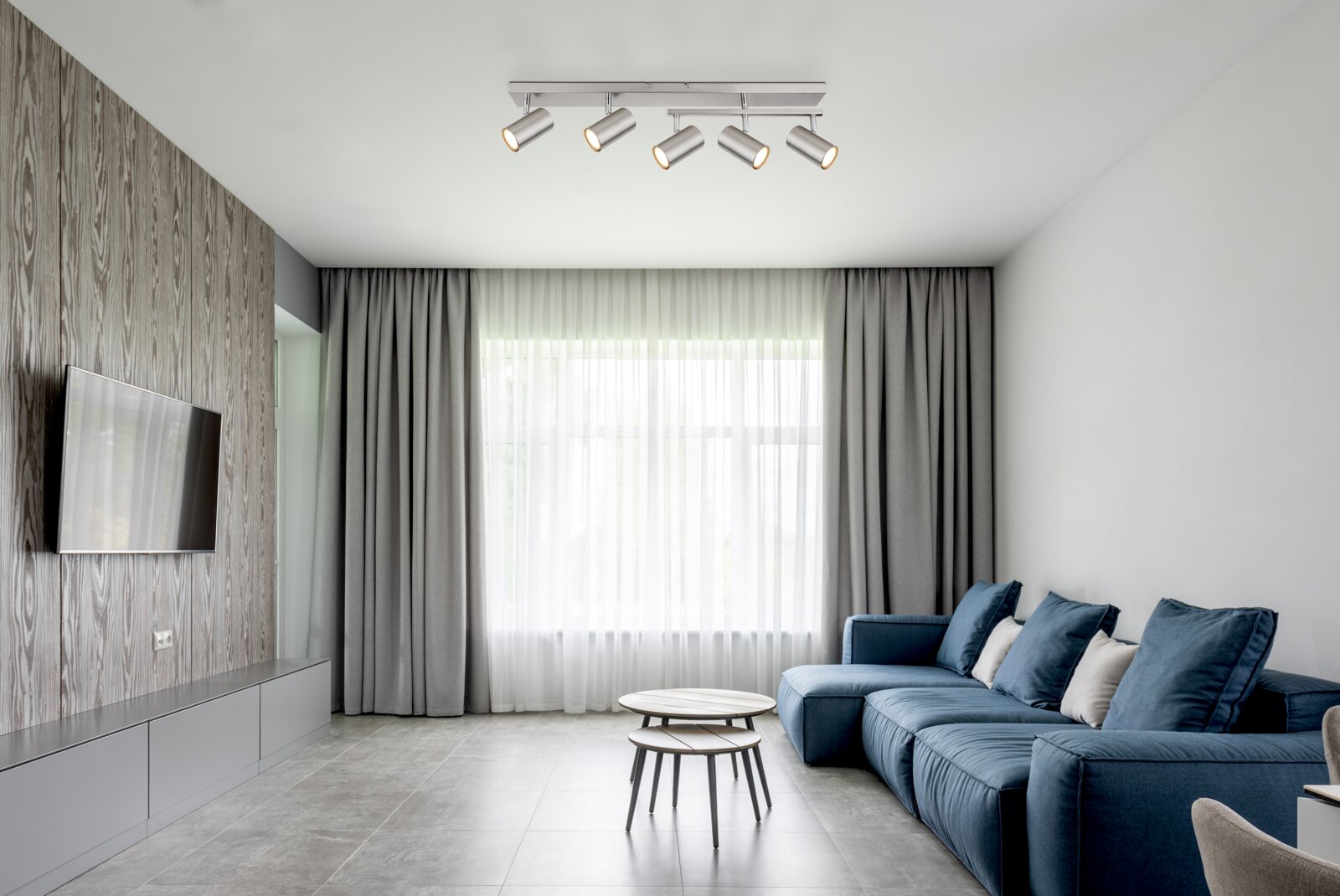 Moderne Deckenstrahler mit fünf verstellbaren Leuchten in einem stilvollen Wohnzimmer, Perspektive von unten.