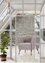 Moderner Sessel mit grauem Stoffbezug und schwarzen Beinen, in einem hellen Raum mit Glaswänden und Pflanzen, aus der Vorderansicht.