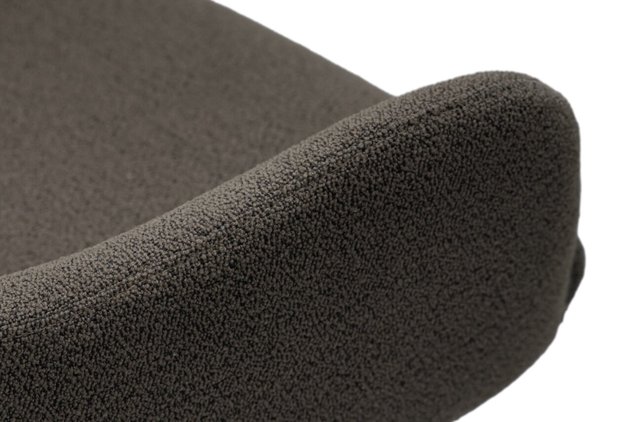 Close-up van een fauteuil met een donkergrijze, gestructureerde stoffen bekleding, gezien vanuit de zijkant