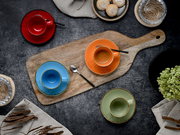 Draufsicht auf buntes Espressotassen- und Untertassen-Set (rot, orange, blau, grün) auf rustikalem Holzbrett mit Löffel, Gebäck und Deko auf dunklem Tisch