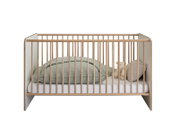Modernes Babybett/Gitterbett aus hellem Holz mit weißen Seitenteilen, frontal in Studioansicht, mit Matratze, Decke, Kissen und Teddy