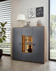 Modernes Highboard mit grauen Türen und Holzrahmen, dekoriert mit einer Lampe und Kunstobjekten, frontal fotografiert.