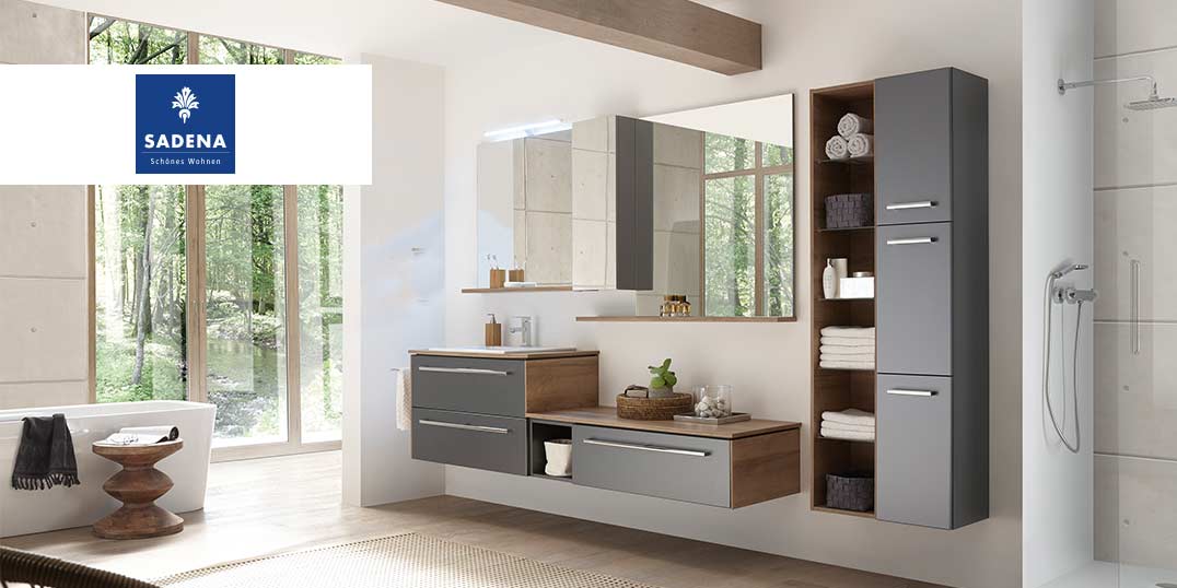 Helles Badezimmer mit grauen Schränken, einem Spiegel und einer Badewanne. Logo Sadena