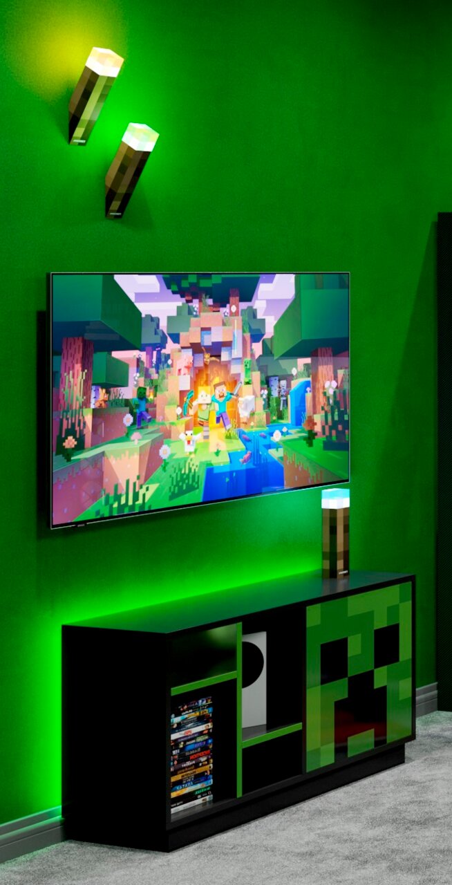 Schwarzes Gaming-TV-Lowboard mit grünem Pixel-Design (Creeper-Motiv) unter einem an der Wand montierten Fernseher, grüne LED-Ambientebeleuchtung und Minecraft-Fackel-Lampen; Perspektive: leicht schräg von vorne.