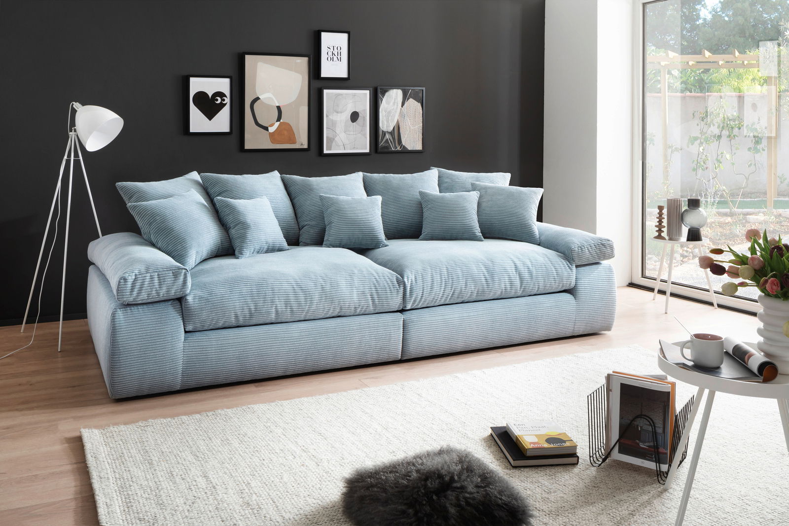Großes, hellblaues Sofa mit mehreren Kissen in einem modernen Wohnzimmer, seitliche Perspektive.