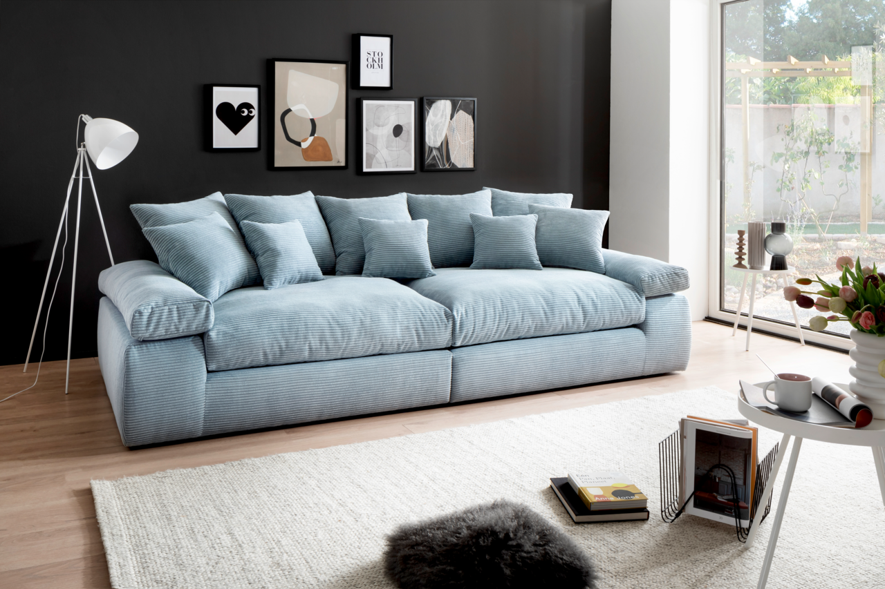 Großes, hellblaues Sofa mit mehreren Kissen in einem modernen Wohnzimmer, seitliche Perspektive.