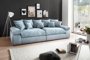 Großes, hellblaues Sofa mit mehreren Kissen in einem modernen Wohnzimmer, seitliche Perspektive.