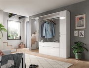 Moderner weißer Hochschrank in einem stilvollen Wohnzimmer, frontal betrachtet, mit hängender Kleidung und dekorativen Elementen.