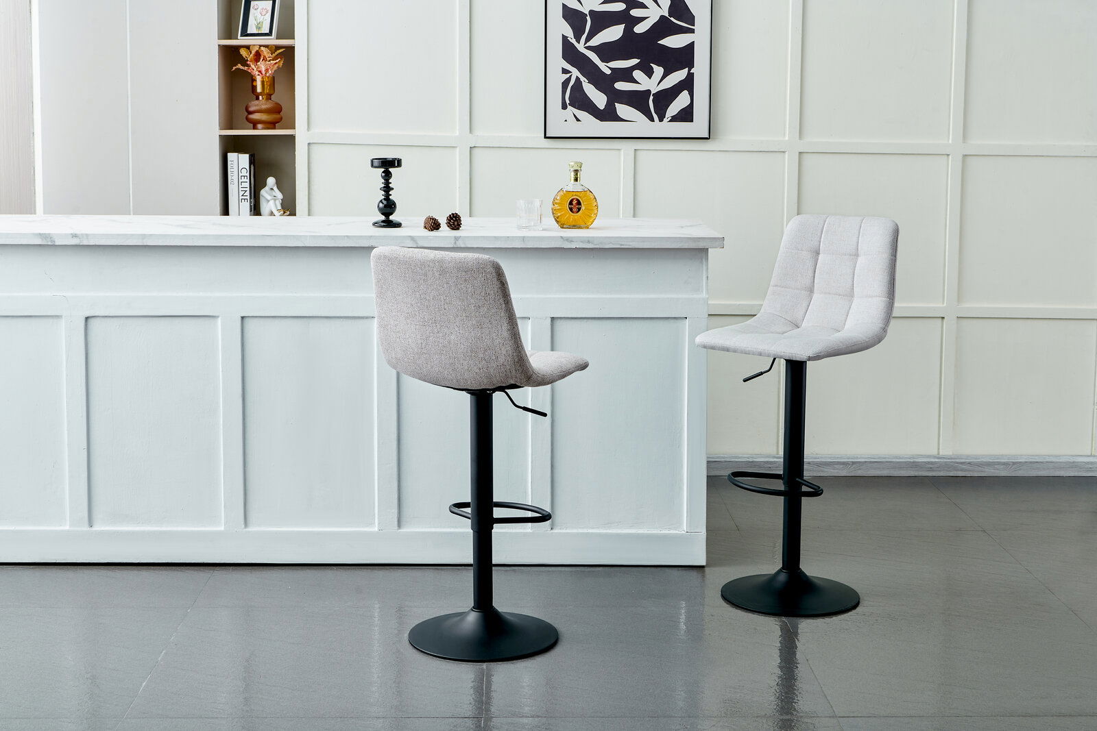 Zwei moderne Barhocker mit schwarzem Fuß und hellgrauer Polsterung, vor einer weißen Theke in einem stilvollen Raum, seitliche Perspektive.
