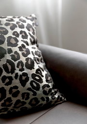 Zierkissenhülle mit Leopardenmuster auf einem Sofa, seitliche Perspektive