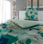 Bett mit Wendebettwäsche in Grün- und Blautönen mit floralem Muster, seitliche Perspektive