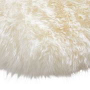 Nahaufnahme eines runden Schaffell-Sitzkissens mit weicher, flauschiger Textur in cremeweißer Farbe.