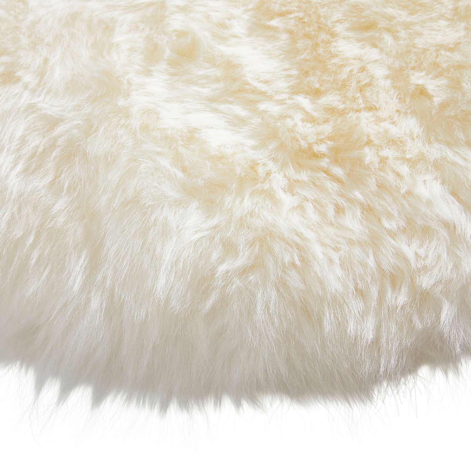 Nahaufnahme eines runden Schaffell-Sitzkissens mit weicher, flauschiger Textur in cremeweißer Farbe.