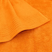 Nahaufnahme eines orangefarbenen Handtuchs mit dekorativen Streifen am Rand, von oben fotografiert.