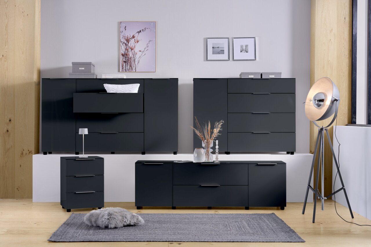 Modernes Sideboard-Set in dunklem Grau, bestehend aus mehreren Schränken und Schubladen, in einem stilvoll eingerichteten Raum mit Holzfußboden und dekorativen Elementen. Frontalansicht.