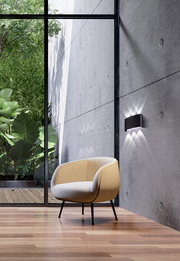 Moderne Wandleuchte an einer Betonwand in einem stilvollen Raum mit Blick auf einen grünen Garten, seitliche Perspektive.