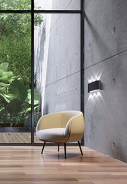 Moderne Wandleuchte an einer Betonwand in einem stilvollen Raum mit Blick auf einen grünen Garten, seitliche Perspektive.