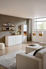 Moderne Wohnzimmeransicht mit eleganter weißer Vitrine und Sideboard, dekoriert mit Vasen und Büchern, aus der Perspektive eines gemütlichen Sofas.