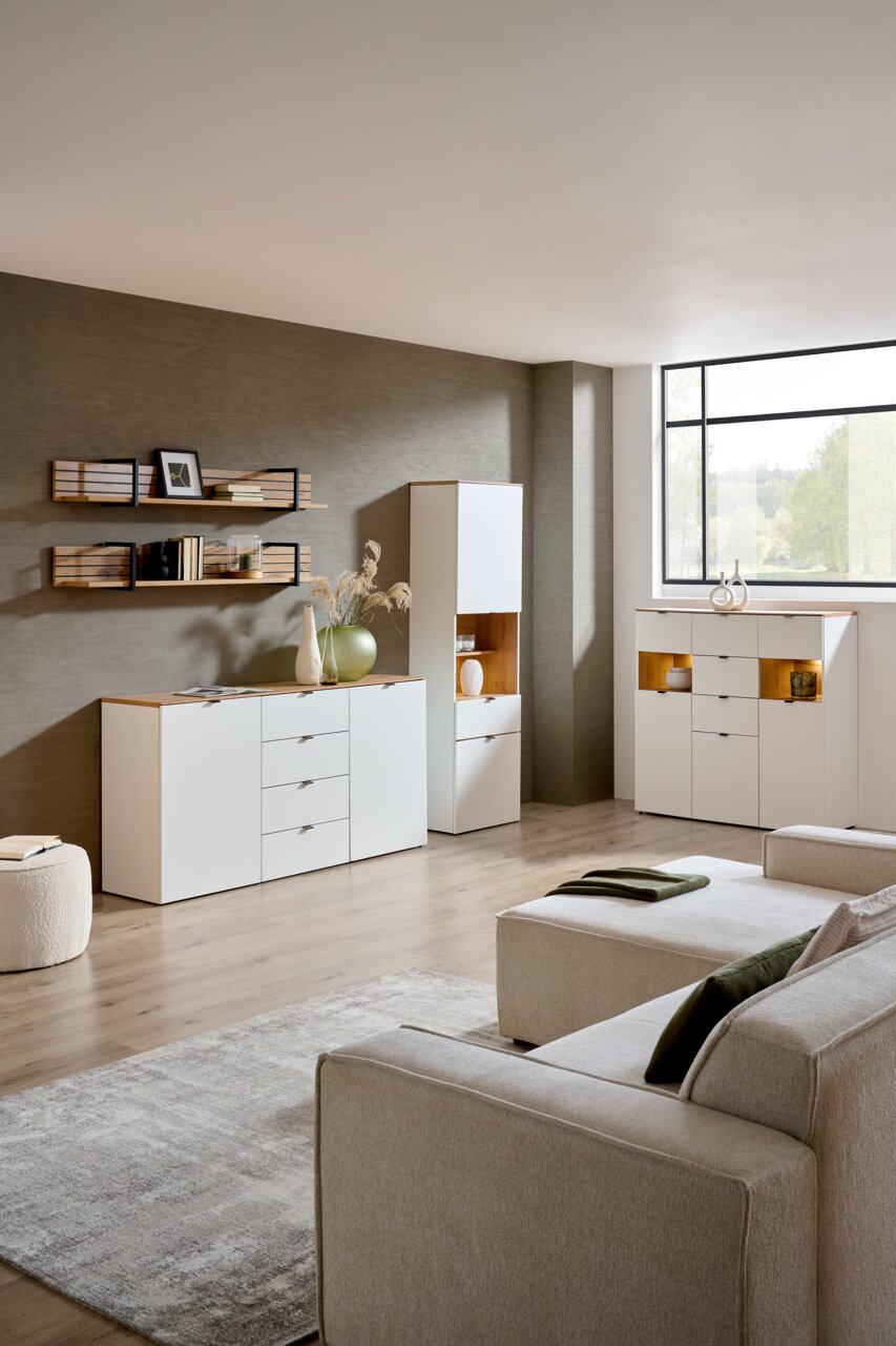 Moderne Wohnzimmeransicht mit eleganter weißer Vitrine und Sideboard, dekoriert mit Vasen und Büchern, aus der Perspektive eines gemütlichen Sofas.