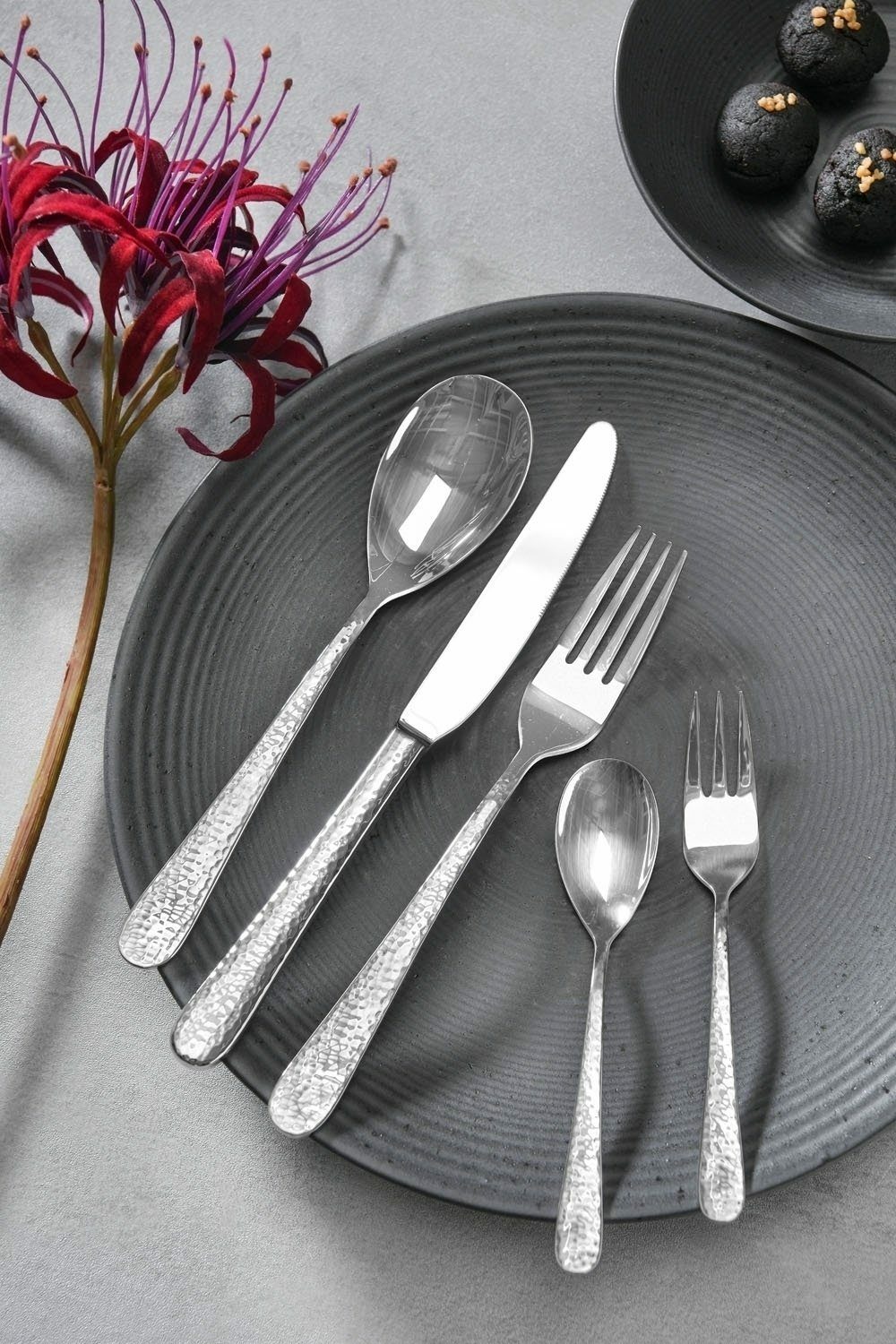 Besteckset Stone 30-tlg. auf einem grauen Teller, bestehend aus Messer, Gabel, Löffel, Dessertgabel und Teelöffel, aus der Vogelperspektive fotografiert.
