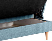 Nahaufnahme eines Schlafsofas mit geöffneter Aufbewahrungsschublade, blaue Polsterung und Holzbeine, seitliche Perspektive
