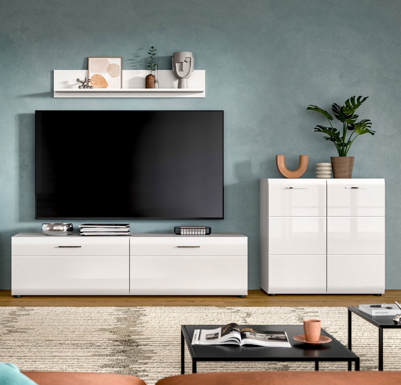 Modernes Wohnzimmer-Setup mit großem Flachbildfernseher über weißem, hochglänzendem TV-Lowboard und passendem Sideboard, dekoriert mit Regal, Pflanzen und Dekoobjekten frontale Perspektive.