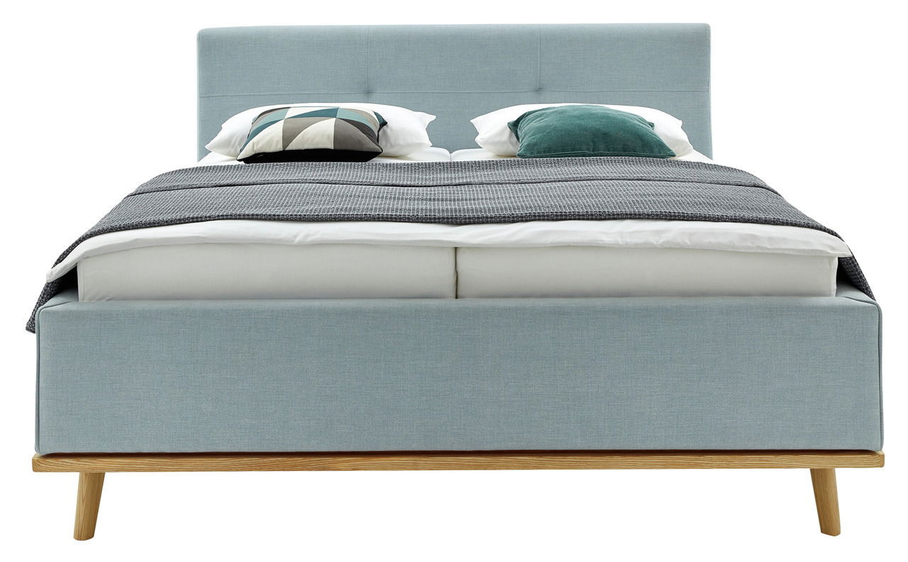 Frontale Ansicht eines modernen Polsterbetts in hellblauem Stoff mit Holzfüßen, dekoriert mit Kissen und einer Decke.