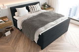 Boxspringbett in modernem Schlafzimmer, seitliche Perspektive, mit grauer Decke und dekorativen Kissen.