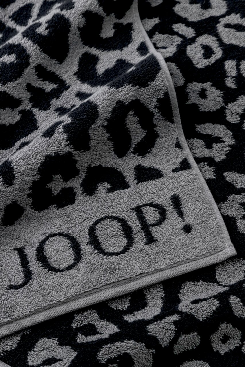 Nahaufnahme eines grauen Duschtuchs mit schwarzem Leopardenmuster und dem Schriftzug 'JOOP!'