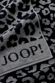 Nahaufnahme eines grauen Duschtuchs mit schwarzem Leopardenmuster und dem Schriftzug 'JOOP!'