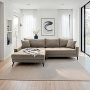 Beige Ecksofa in modernem Wohnzimmer, Perspektive von vorne, mit Kissen und Decke dekoriert.