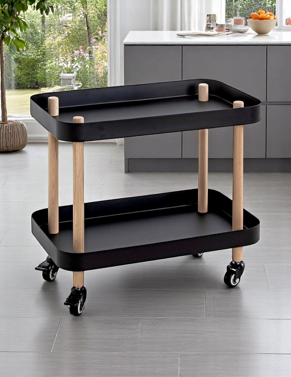 Schwarzer, zweistöckiger Servierwagen mit zwei Tablettablagen, hellen Holzpfosten und vier Rollen in moderner Küche, schräg von vorn fotografiert.