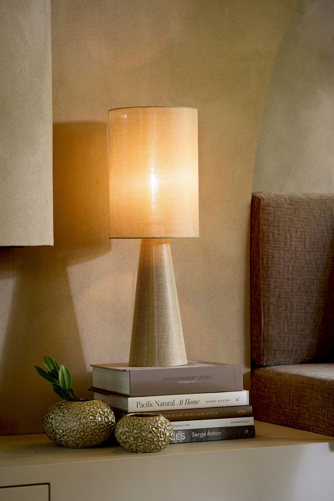 Light&Living Teelicht CAREZZA 9,5cm Stimmungsvolle Tischlampe mit konischem Sockel und warmem Licht, seitliche Perspektive auf einem Tisch mit dekorativen Büchern und Vasen.