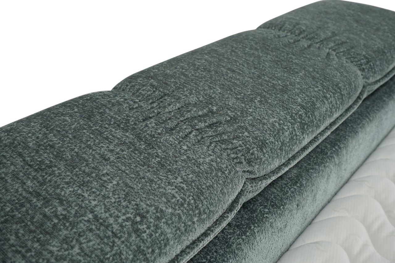 Nahaufnahme eines grauen Boxbetts mit gepolstertem Kopfteil, seitliche Perspektive