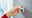 Hand zieht tesa Powerstrip Waterproof von einer grauen Wand ab, seitliche Perspektive