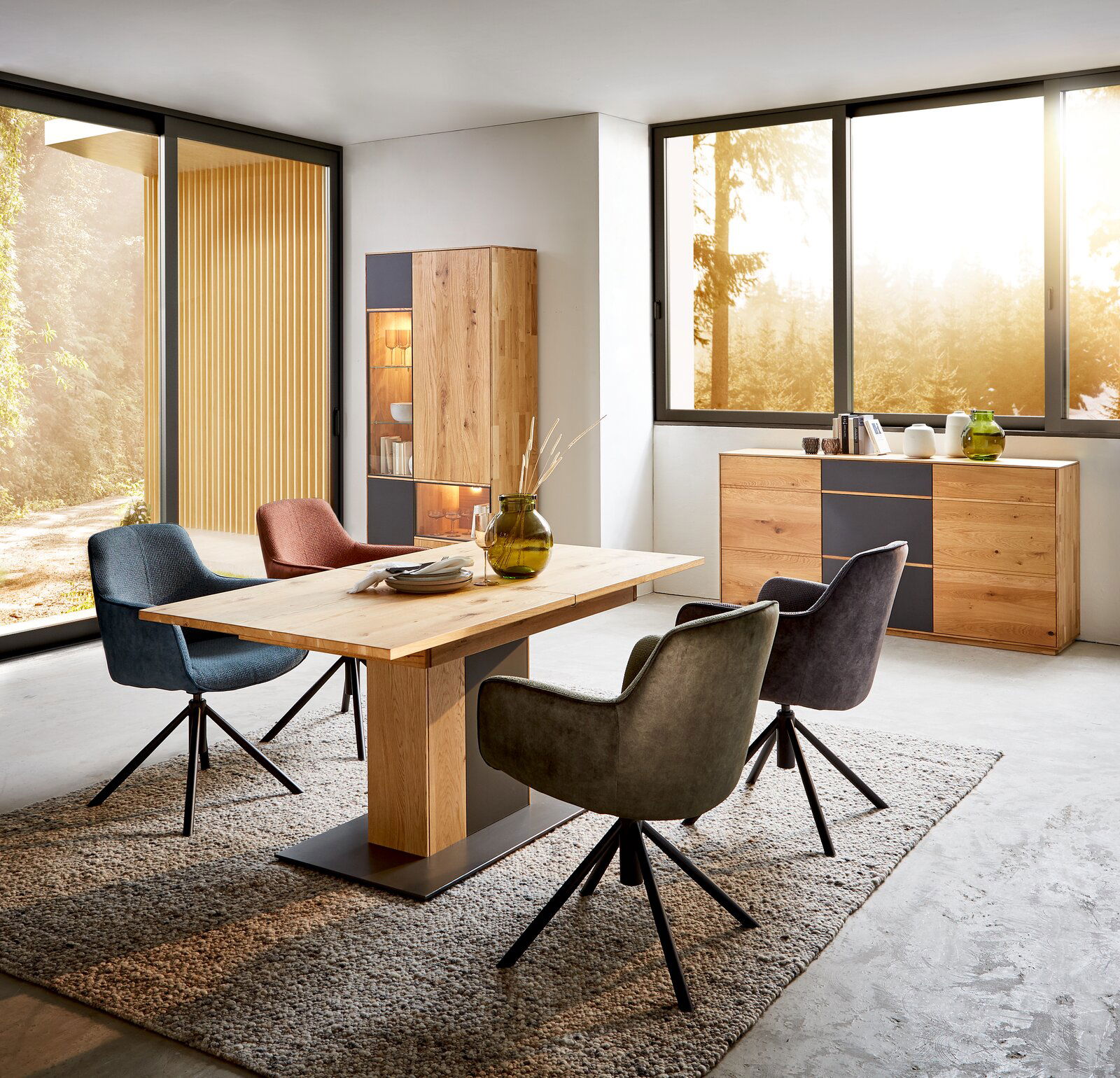 Esszimmer mit modernem Holztisch und vier gepolsterten Stühlen in verschiedenen Farben, seitliche Perspektive