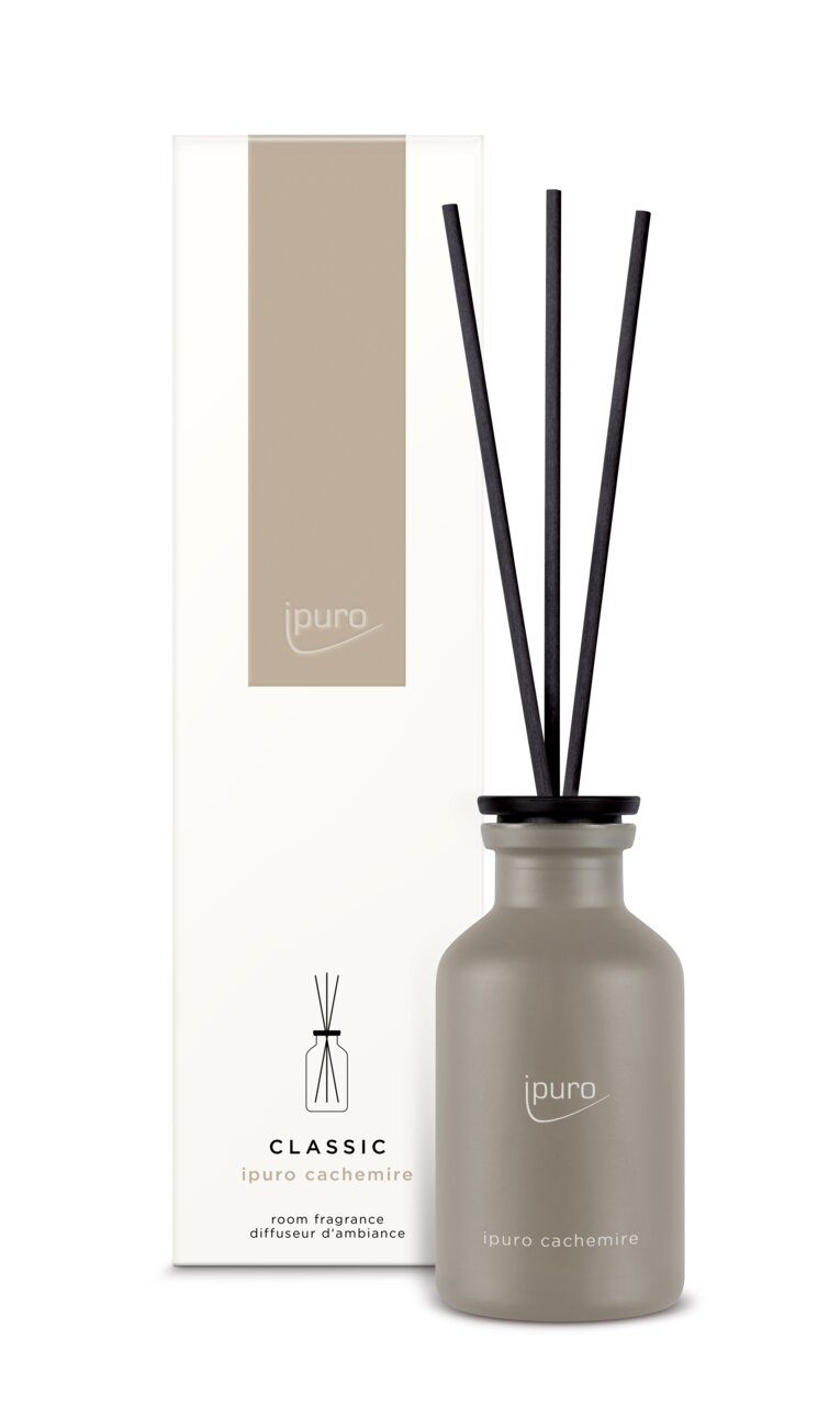 Vorderansicht eines Classic Cachemire Raumdufts von ipuro mit eleganter grauer Flasche und schwarzen Duftstäbchen, neben der passenden Verpackung.