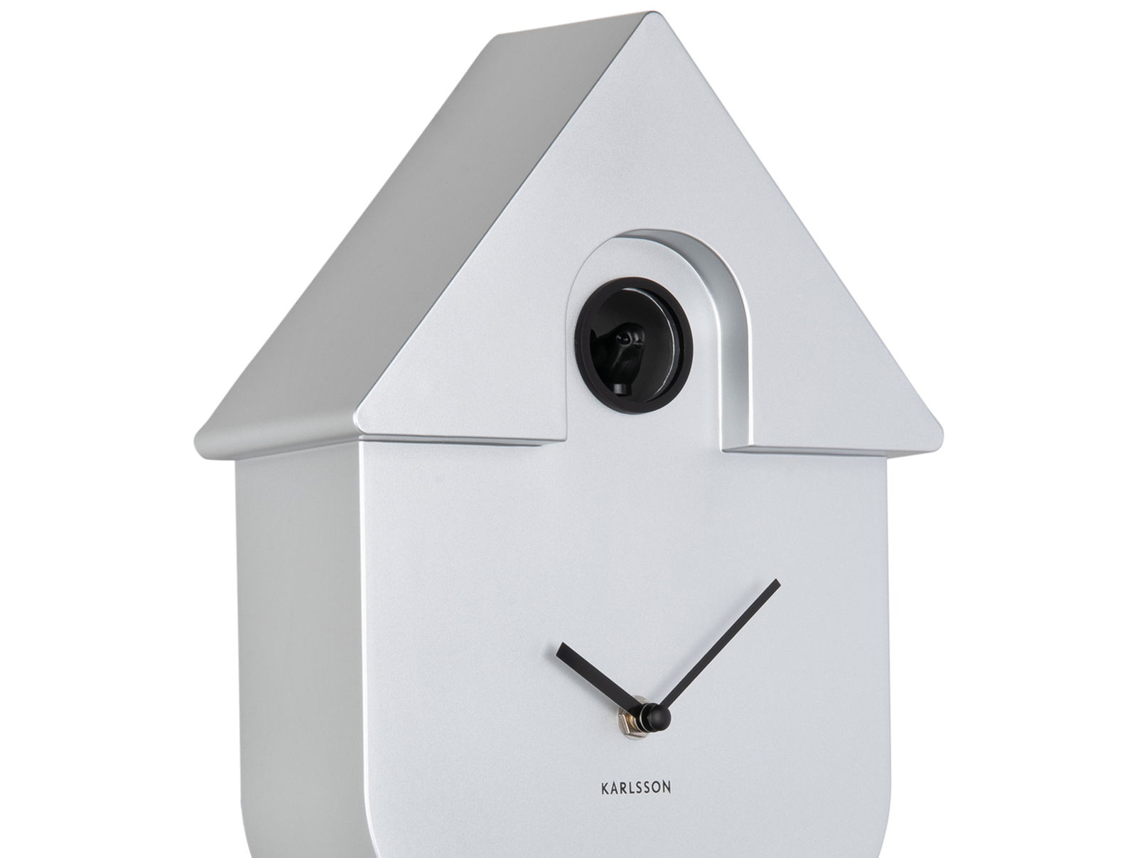 Silberne Wanduhr in Form eines Hauses mit schwarzem Kuckuck und minimalistischen Zeigern, seitliche Perspektive.