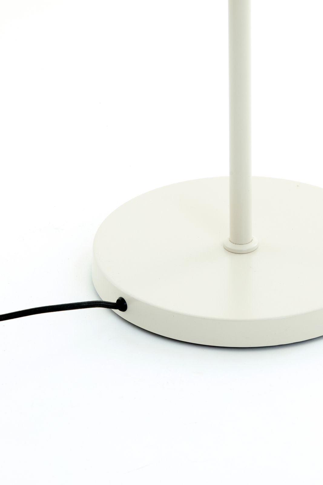 Nahaufnahme der Basis einer weißen Stehleuchte mit schwarzem Kabel