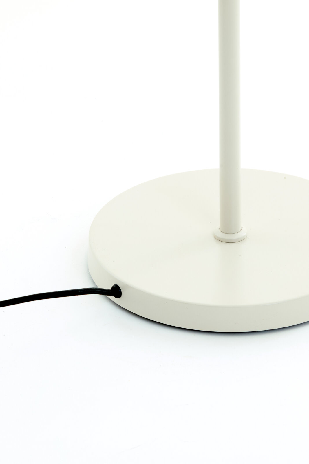 Nahaufnahme der Basis einer weißen Stehleuchte mit schwarzem Kabel