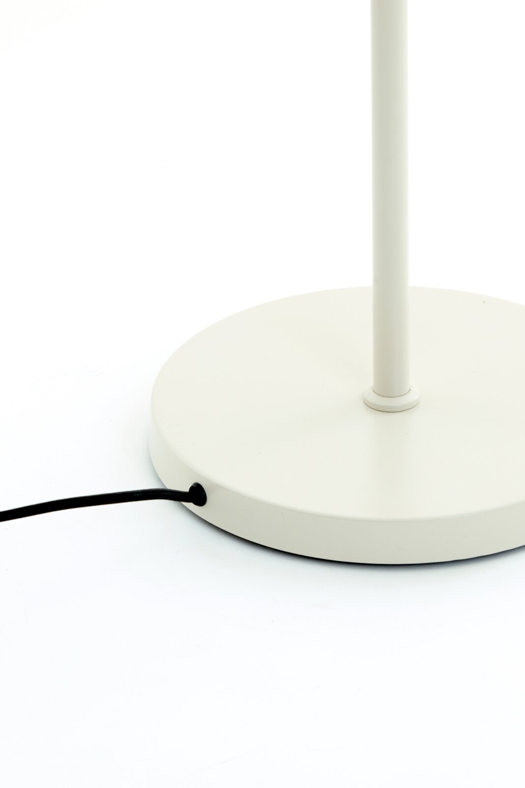 Close-up van de voet van een witte staande lamp met een zwarte kabel